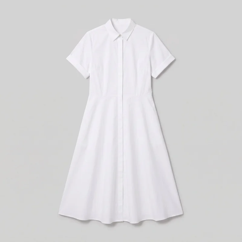 White cotton shirt dress shown laid flat in a mostly complete front view. It has a pointed collar, short sleeves with turned cuffs, a concealed full-length button placket with a visible top button, a defined waist seam, and an A-line skirt ending at a softly curved below-knee or midi-length hem.