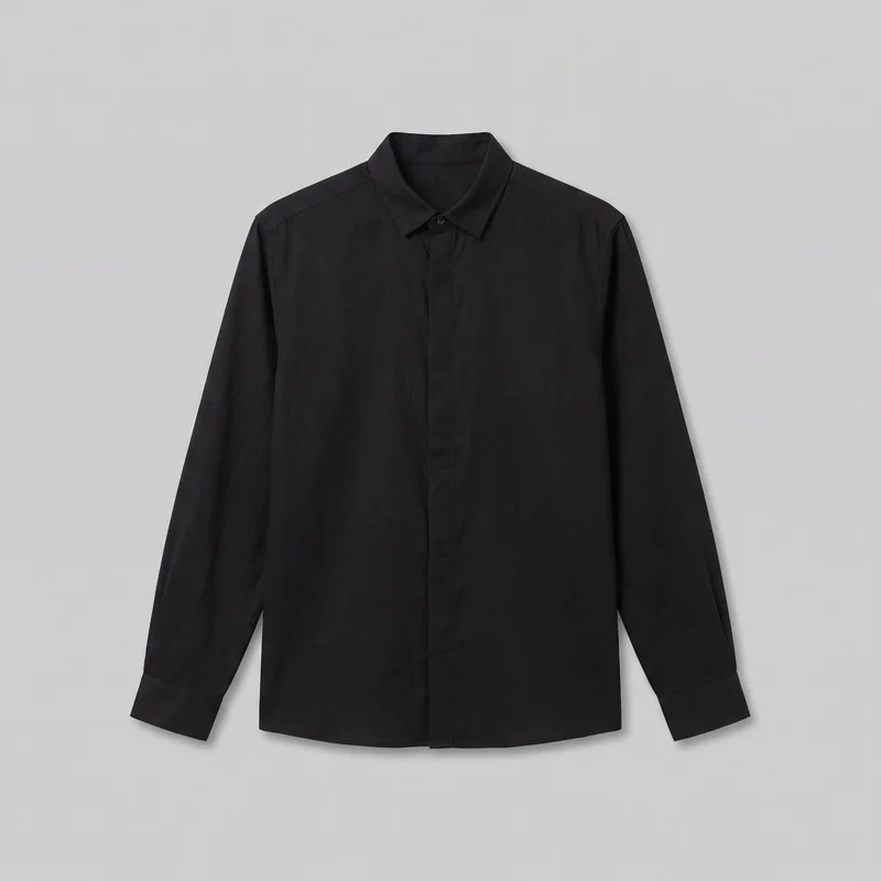 A black grandad shirt is shown laid flat in a centered front view against a plain backdrop. The full-length, regular-fit shirt has long sleeves with simple cuff bands, a pointed fold-down collar, set-in shoulders, a central button placket with a visible top button, and a straight-to-slightly curved hem. No chest pockets or visible logos, prints, embroidery, patches, or embellishments are present.
