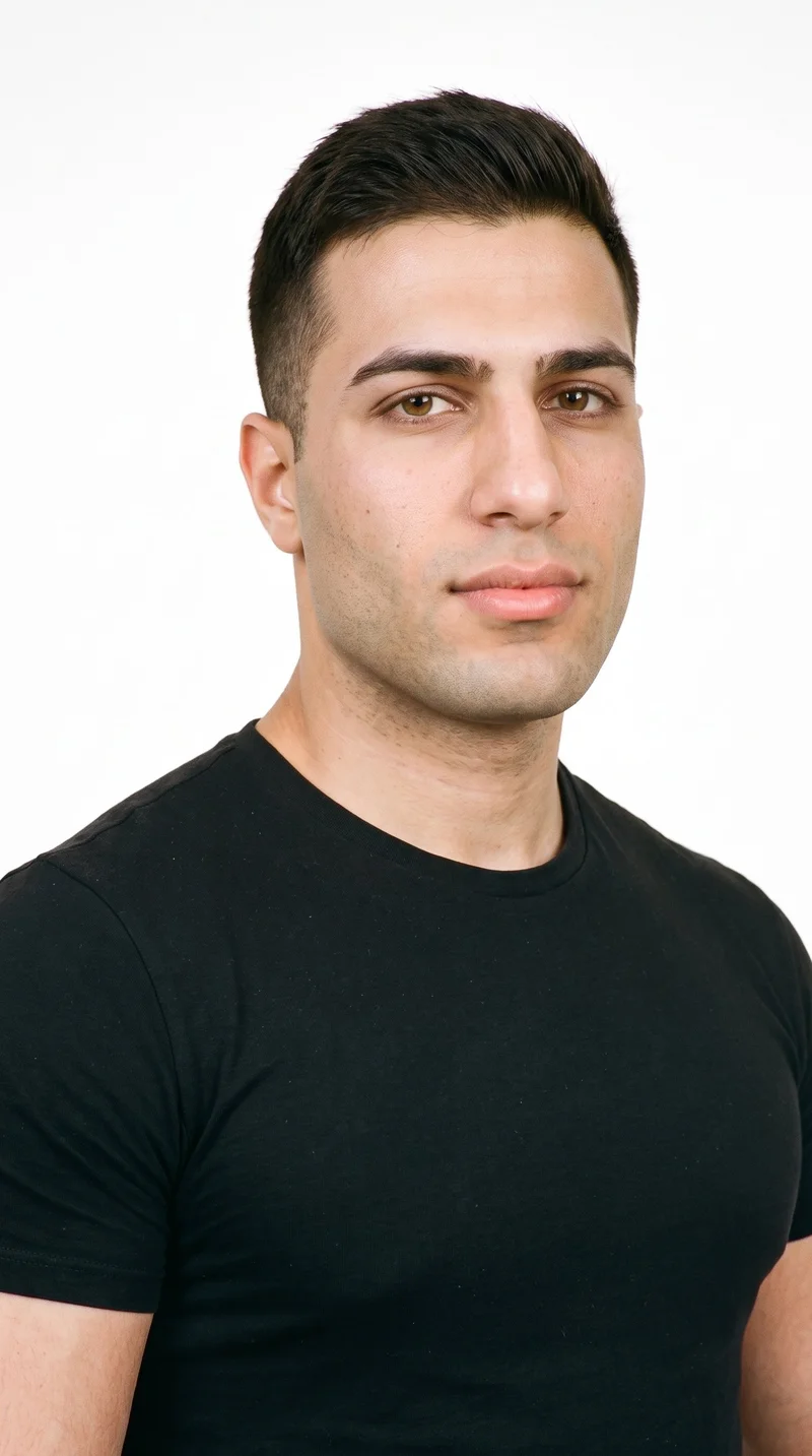A 23-year-old Arab man with medium olive skin and a greenish-golden undertone. His triangular face has a wide jaw that narrows toward the forehead, with medium-thickness eyebrows, brown eyes, and full lips. His dark-brown hair is styled in a short tapered crew cut, slightly longer on top than at the sides, and he is clean-shaven with smooth facial skin.