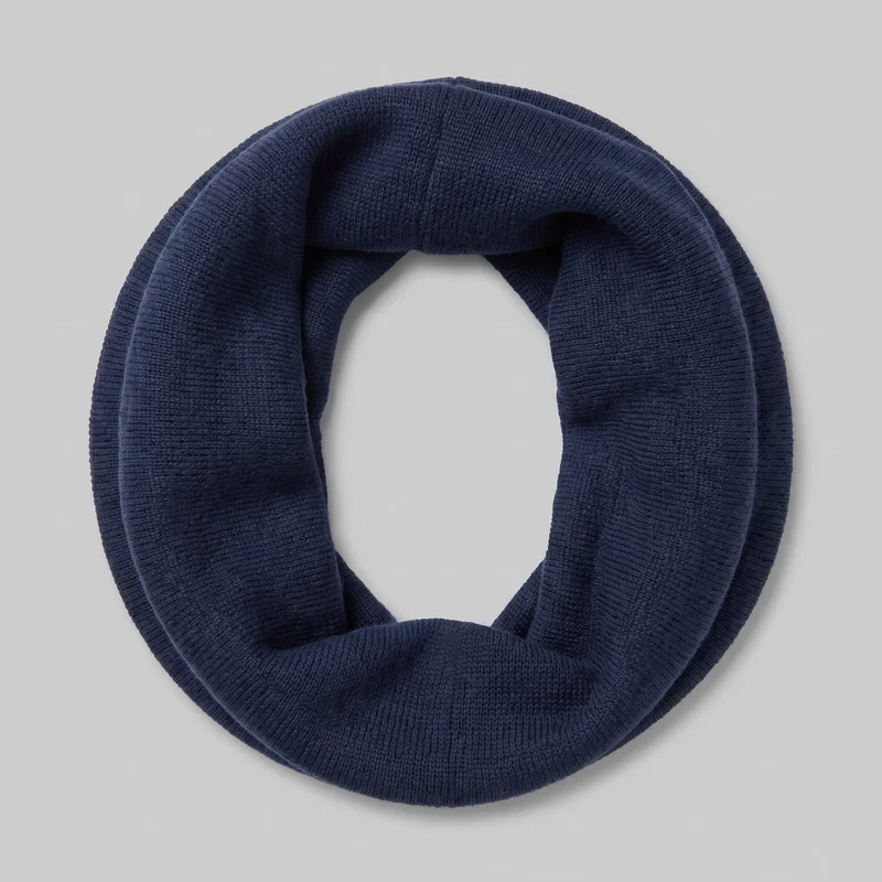 A complete navy infinity scarf is arranged flat in an oval ring, showing its wide tubular knit band, central opening, and overlapping folded section. Ribbed borders run along both long edges, with softly rounded folded edges and no visible closures or embellishments.