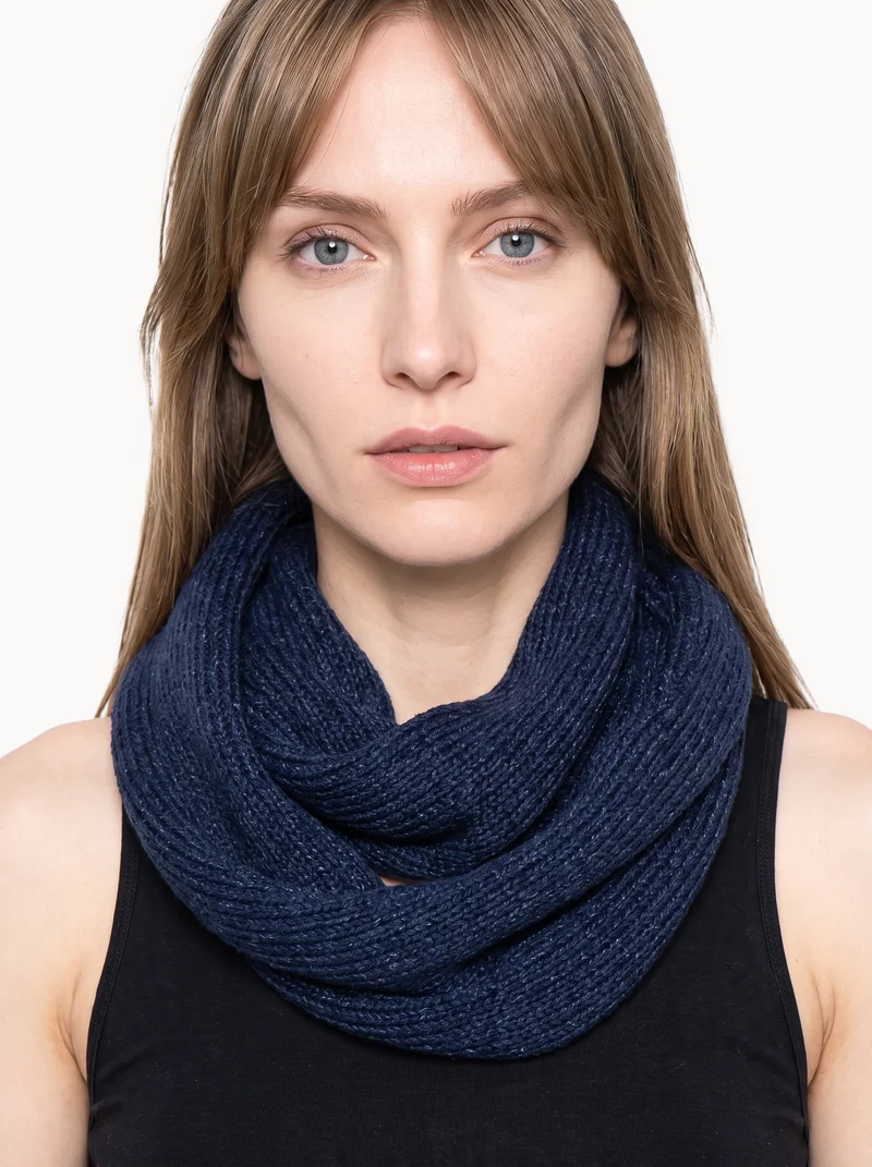 A woman wears a women's navy snood around her neck, shown from the front with one hand under her jaw. The subject is framed from the neck upward against a Chantilly Lace backdrop.