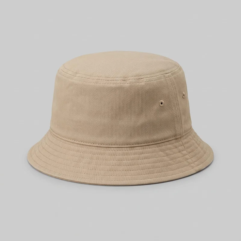 A standalone beige men's bucket hat is shown in a close front-side view. The full crown and most of the downward-sloping brim are visible, along with the top crown seam, lower crown seam, vertical side panel seams, embroidered ventilation eyelets, and multiple parallel rows of stitching around the brim. No logos, prints, patches, or embellishments are visible.